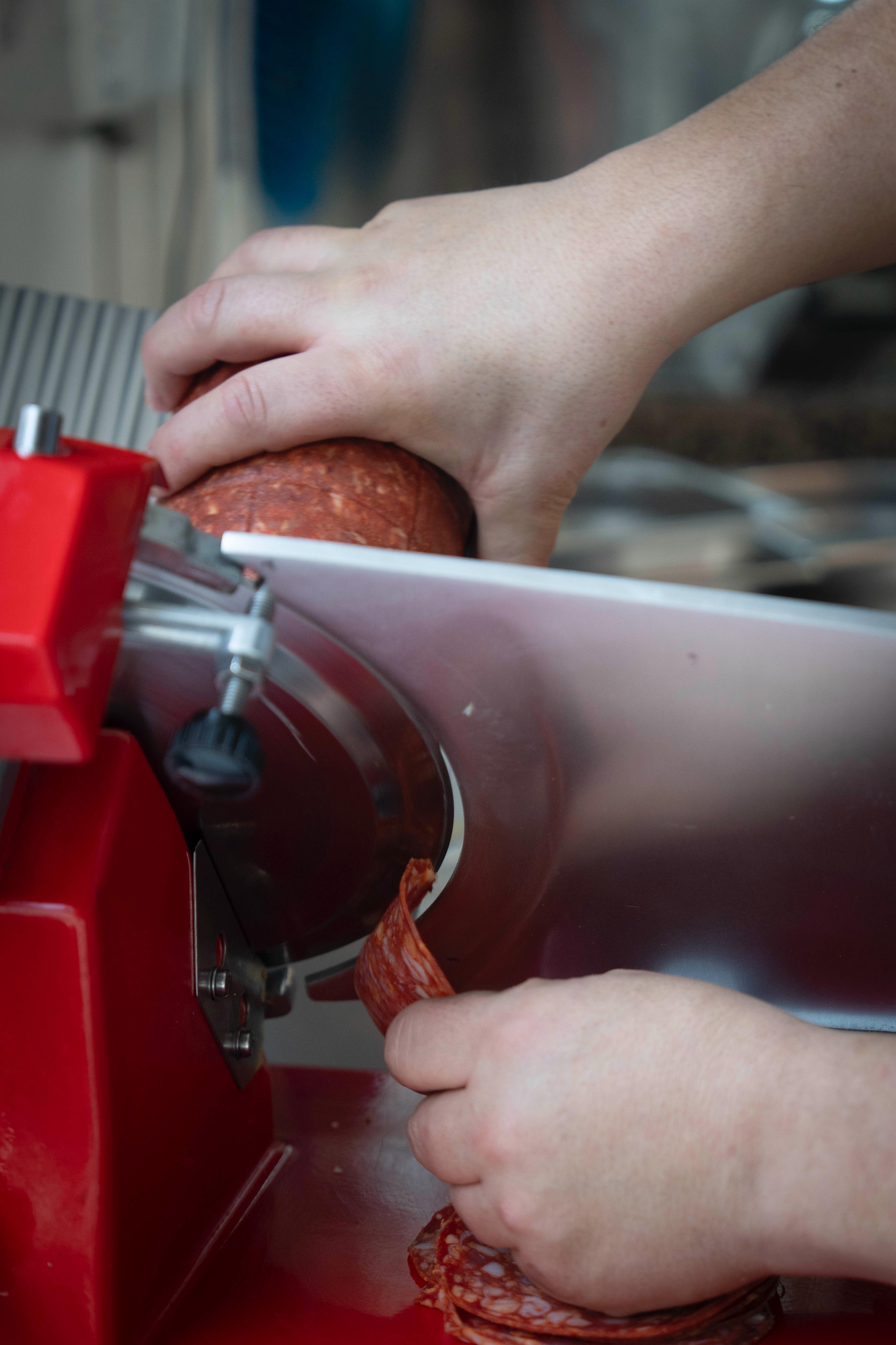 Slicing salami on a meat slicer at Kalura, Antwerp